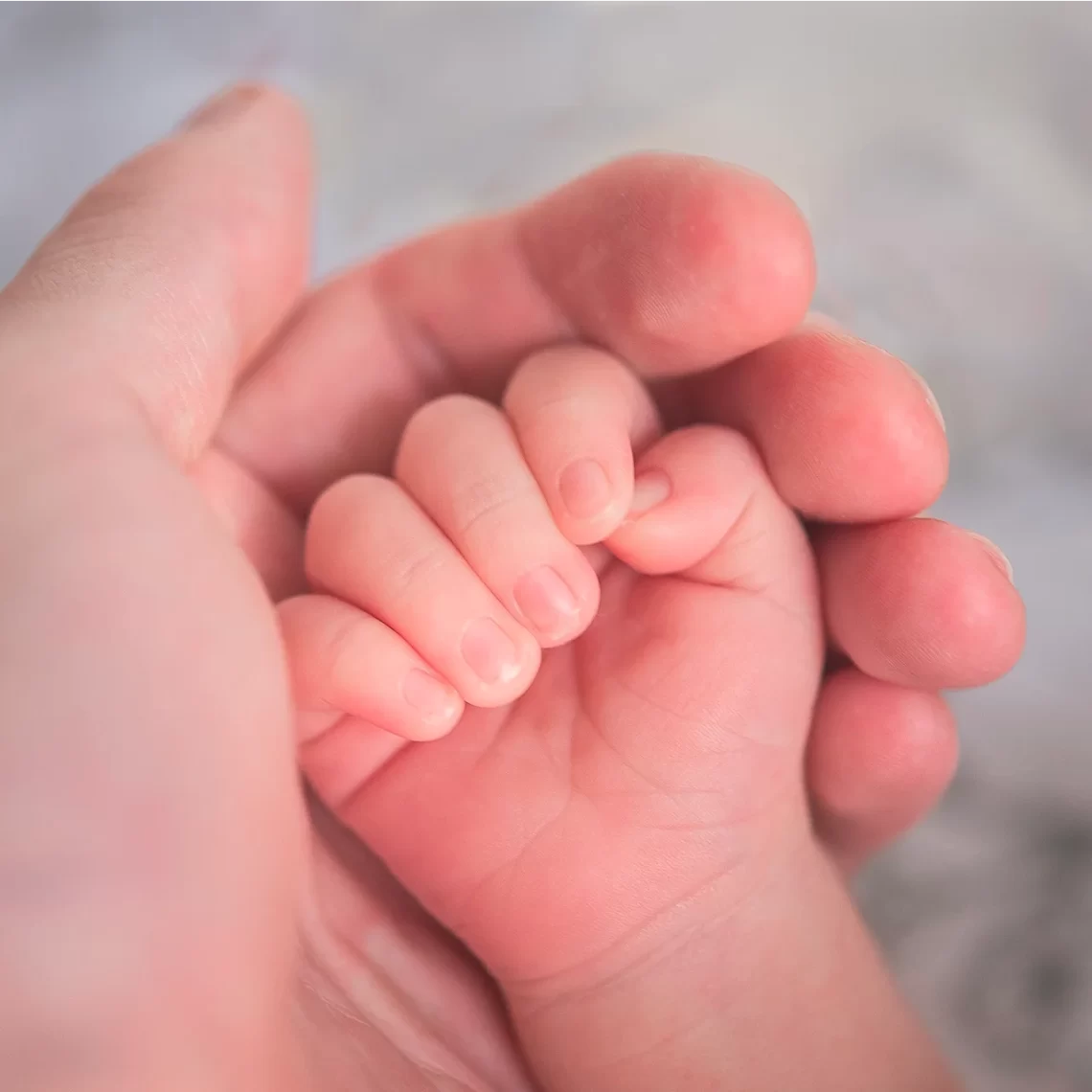 okno życia, w którym rączka niemowlaka trzymana jest w dłoni opiekunki